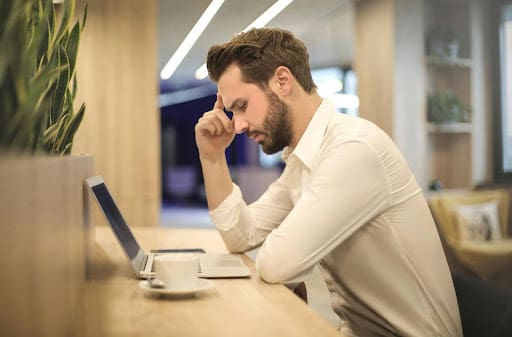 A tense man reading a blog about yoga stretches you can do at your desk.