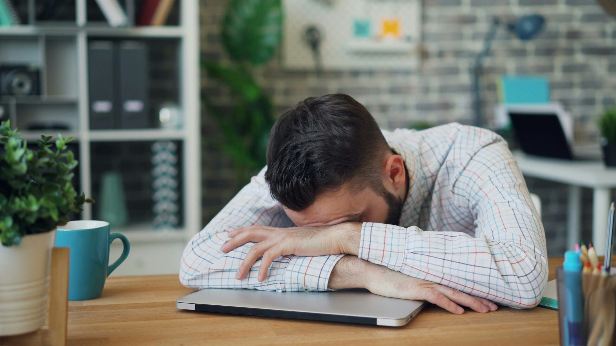 A tense man reading a blog about yoga stretches you can do at your desk.