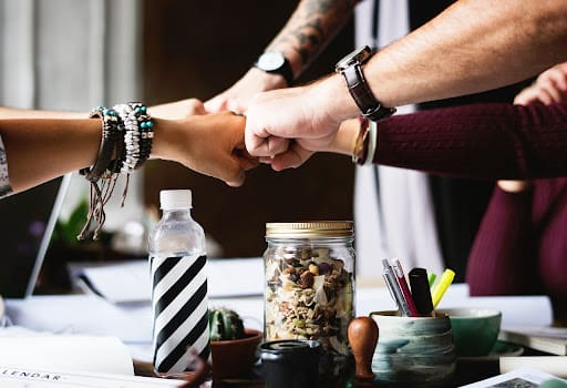 Employees in Alameda CA fist bumping after employee morale is boosted in the workplace